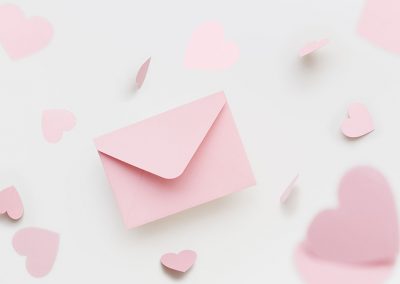 Flying pink envelope surrounded with flying pink hearts on the white background. Valentines Day greeting concept